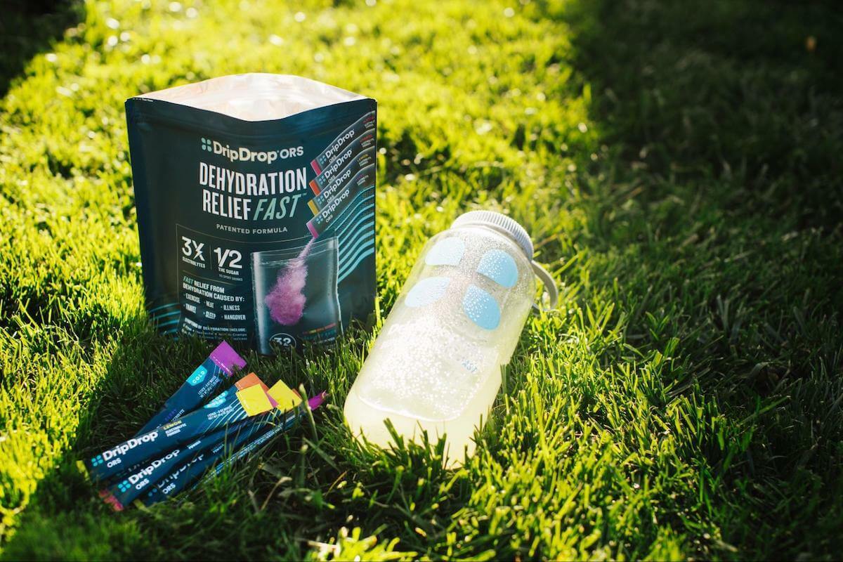 DripDrop ORS pack, sachet, and tumbler on the grass