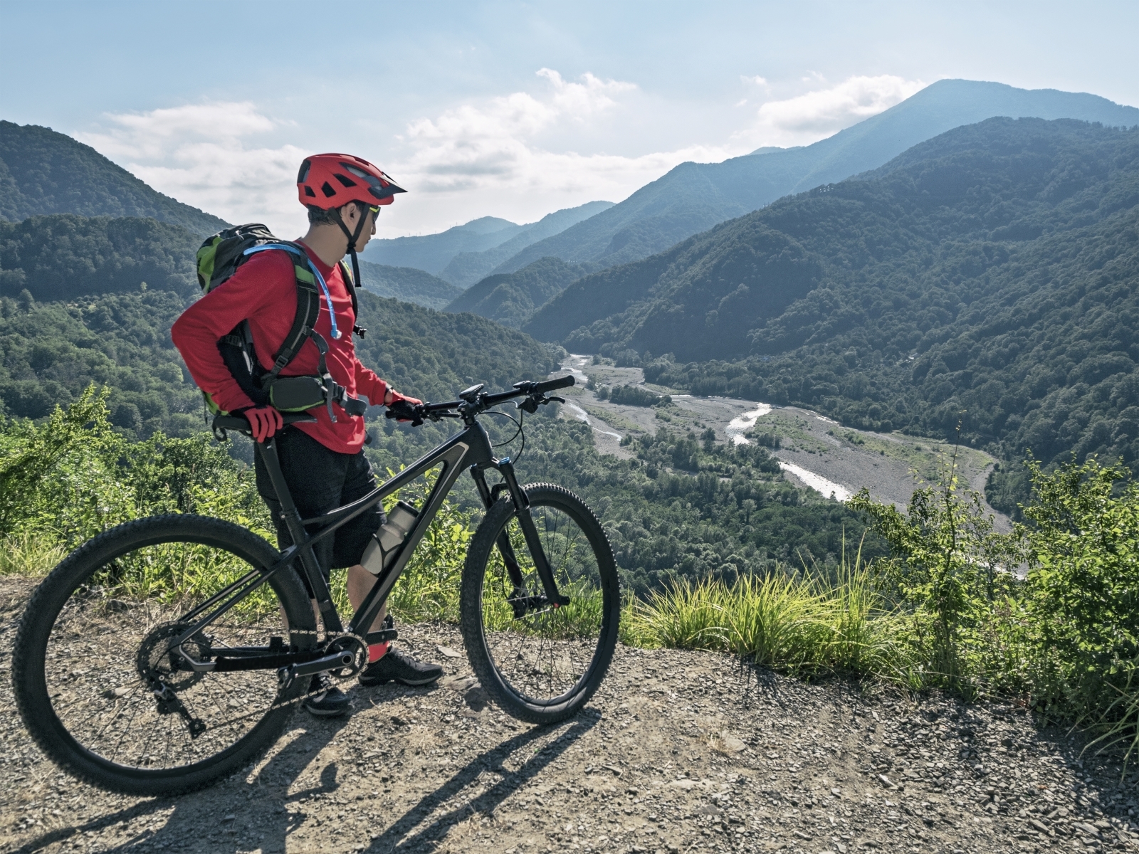 hydration bladder: Man looking down at the view after riding his mountain bike