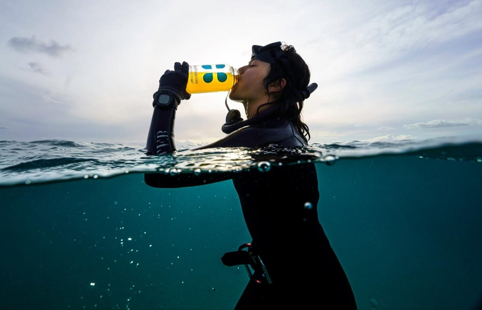 Woman drinking DripDrop ORS while in the water