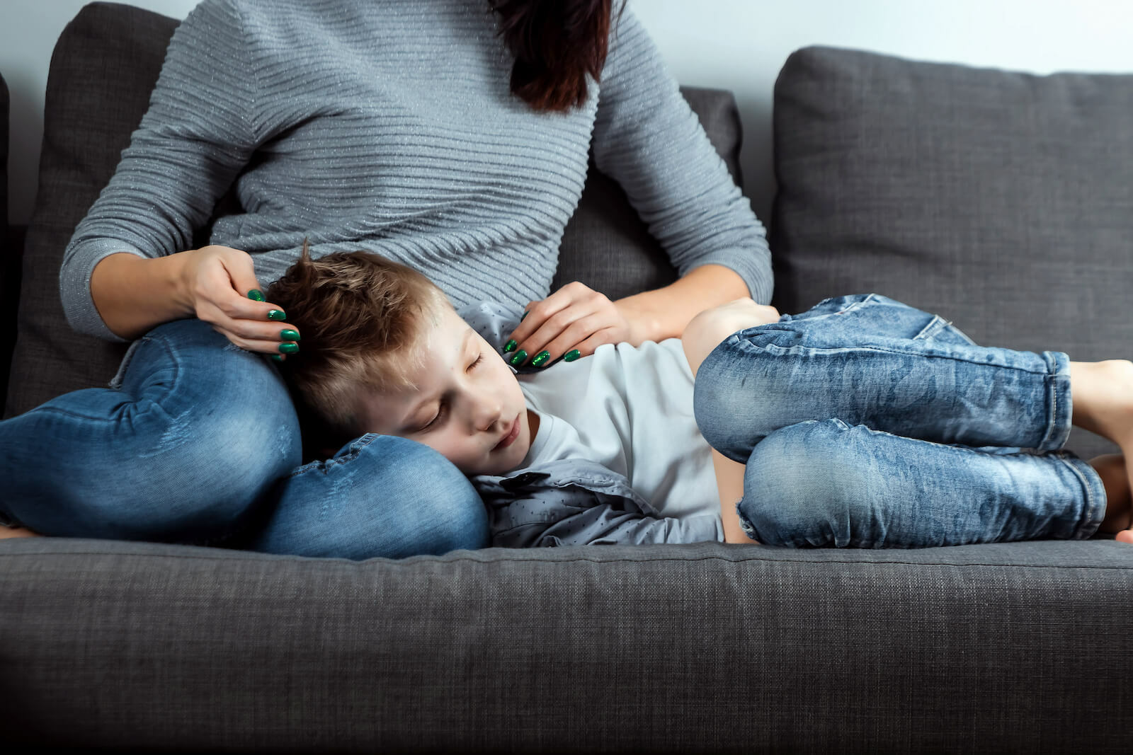 Ginger ale benefits: boy with a stomachache laying on his mother's lap