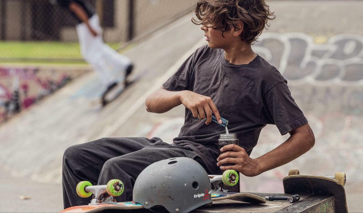 What does a dehydration headache feel like: boy with a skateboard pouring DripDrop ORS into a tumbler