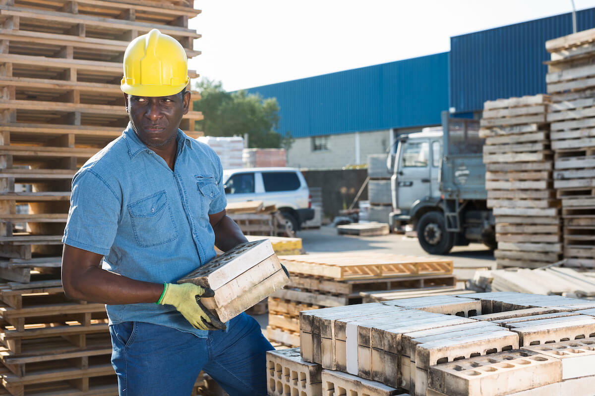 Construction working carrying hollow blocks under the heat of the sun