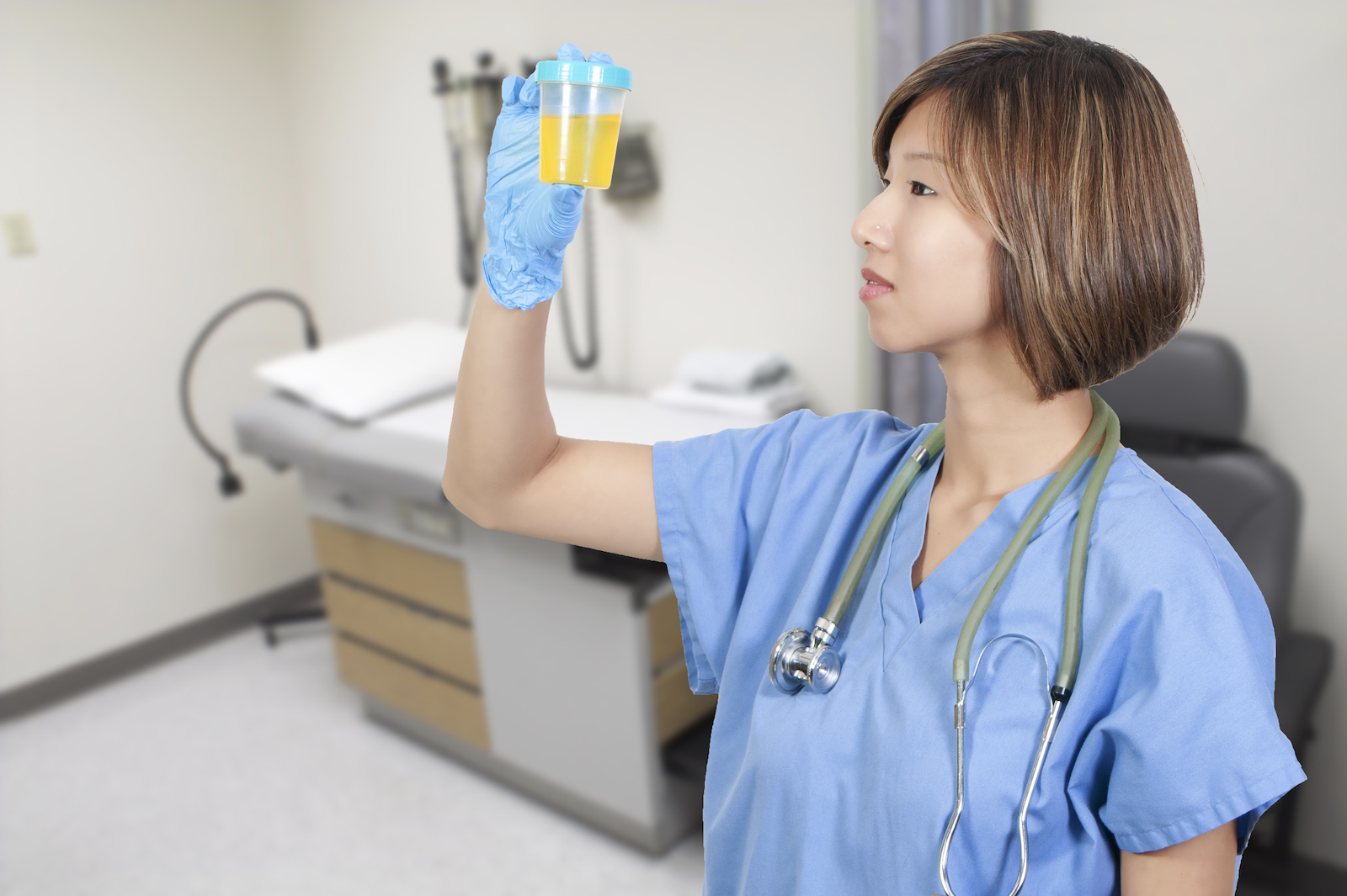 cloudy urine dehydration: Female doctor looking at a urine specimen