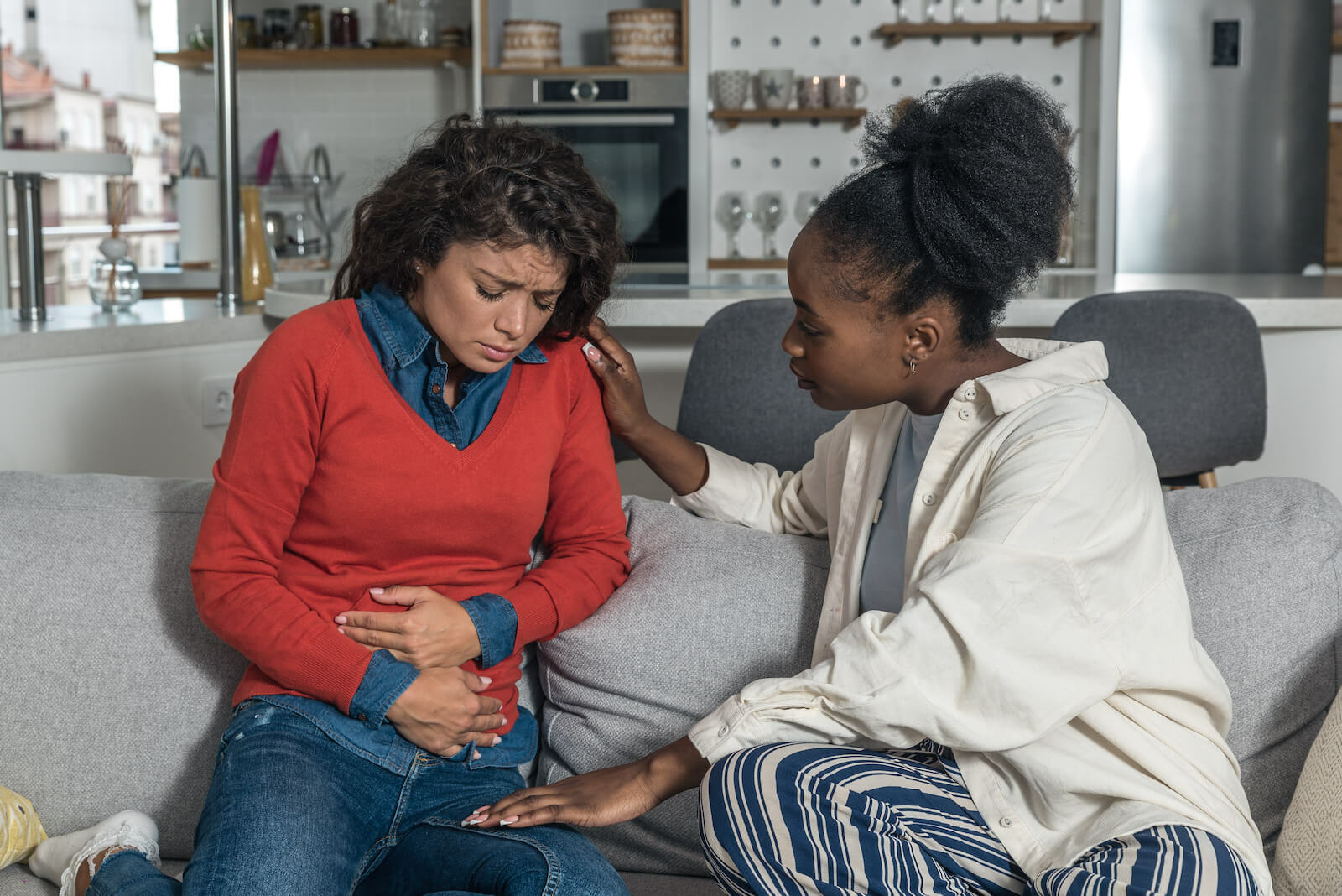 Woman comforting her friend who's experiencing stomach pains