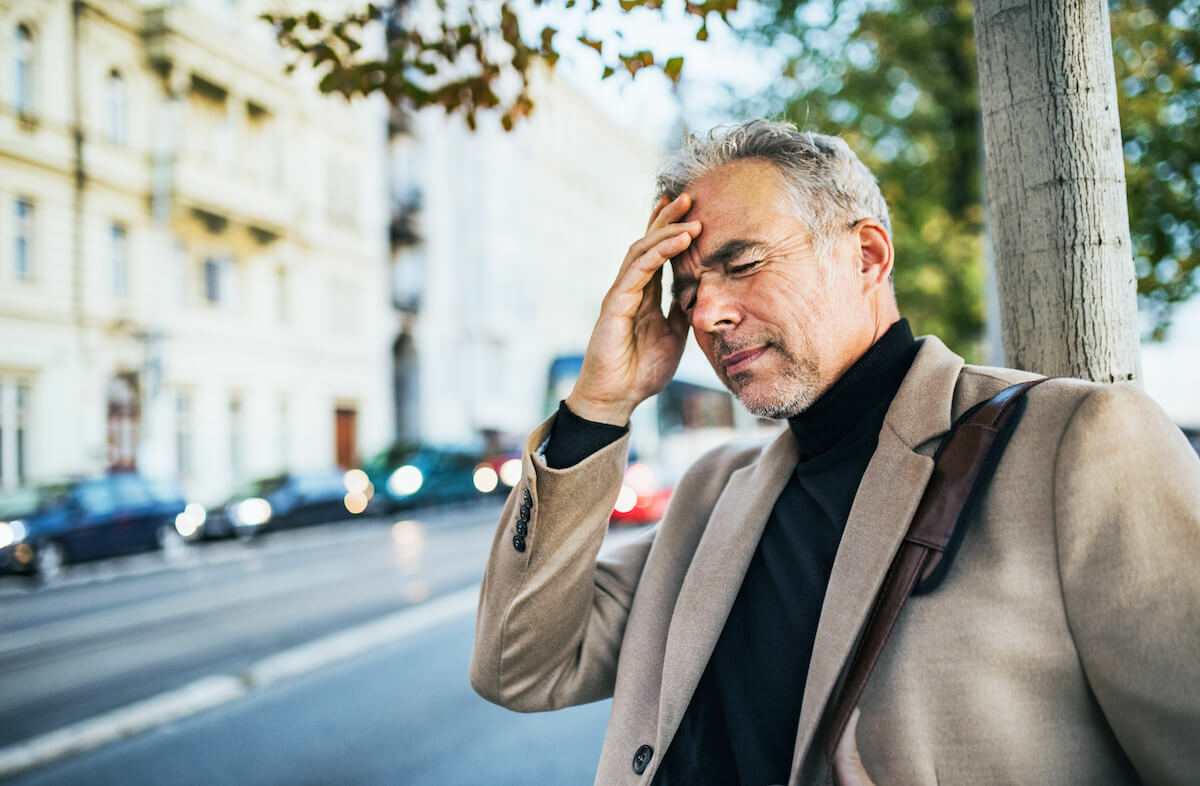 What does a dehydration headache feel like: man with a headache touching his forehead