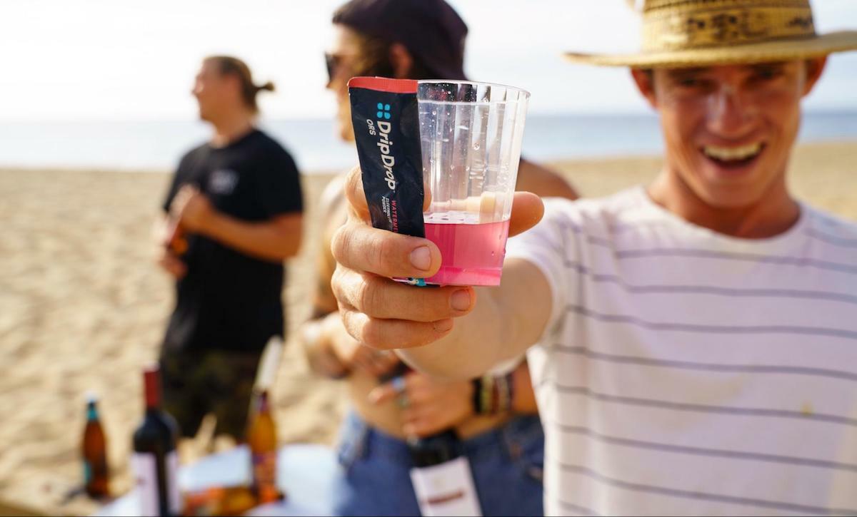 Drinks for dehydration: person holding a DripDrop ORS sachet and a cup