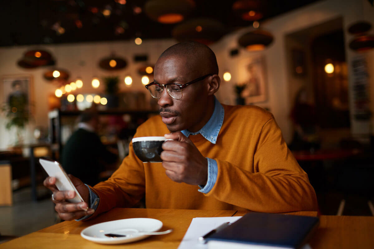 Caffeine dehydration: man using his phone while drinking coffee