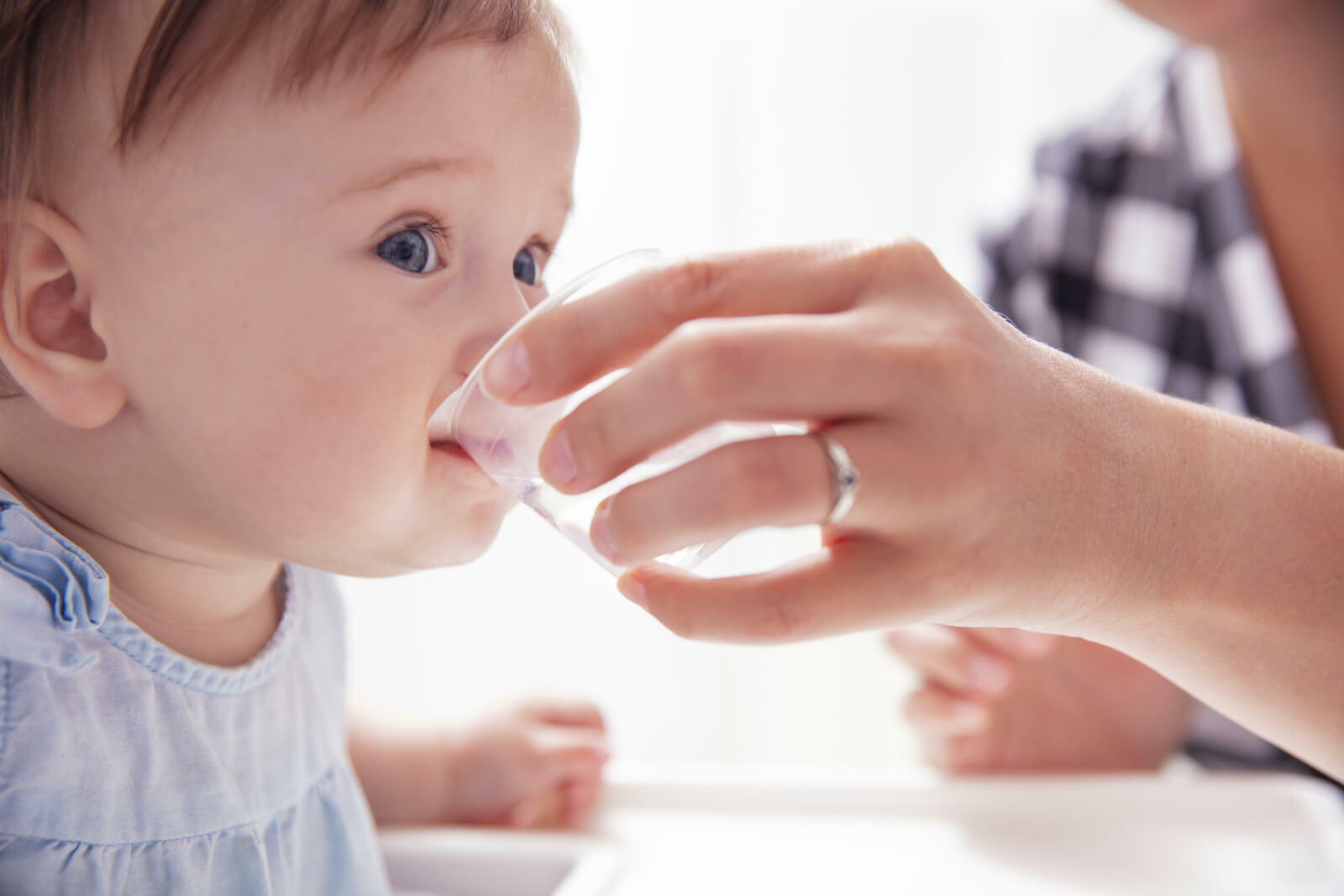 Oral rehydration salts: person helping a baby drink water